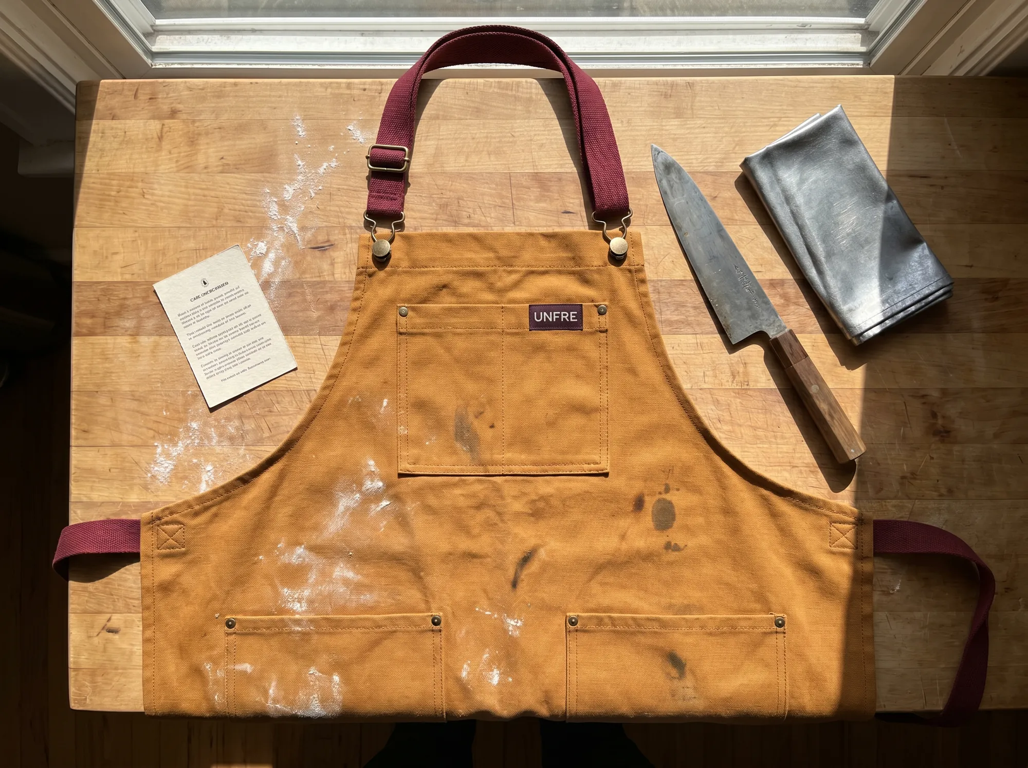 Unfre Working Apron (Restaurant & Kitchen Workwear) — A heavy cotton-canvas apron in natural duck or working amber, with bartacked pockets, replaceable neck strap, and a repair voucher.